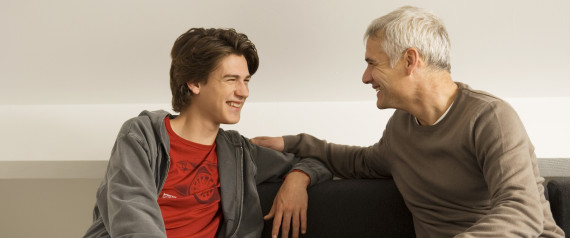 Mature man with his son sitting on a couch and gossiping