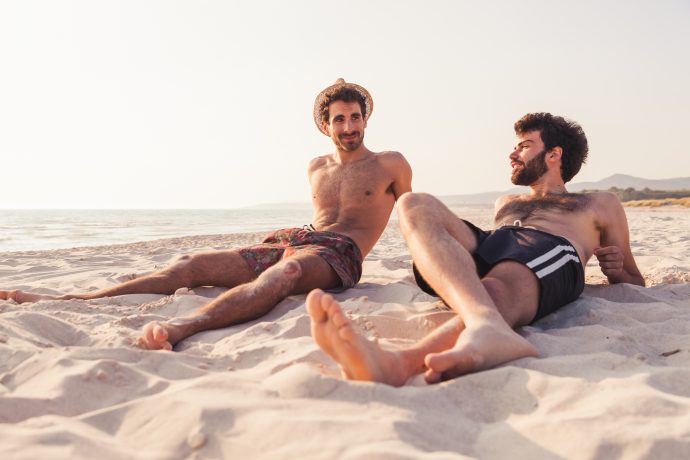 Couple of male friends at sunset on the beach