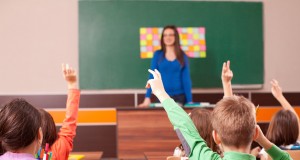 Children in elementary school are raised hand in clasroom