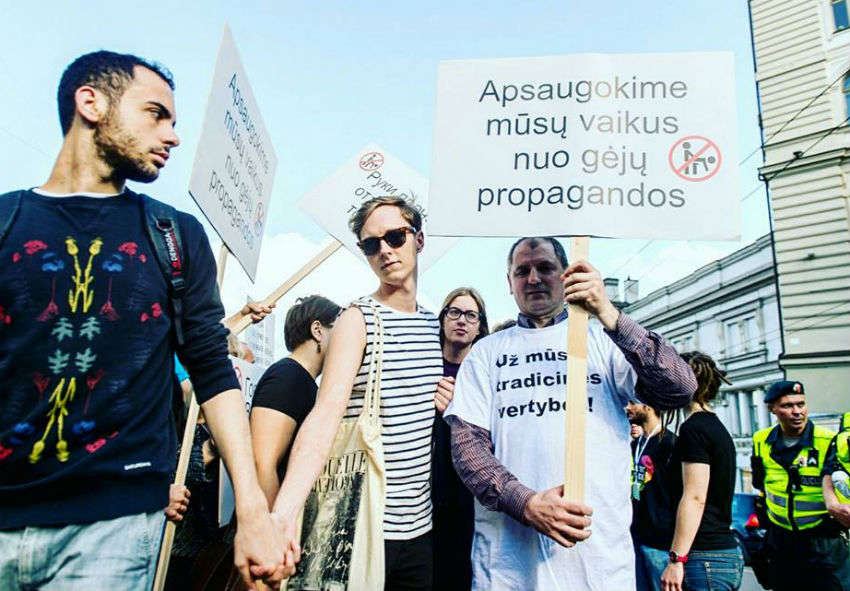 An anti-LGBTI protestor holds a placard at Baltic Pride in 2016 saying 'Save our children from gay propaganda'