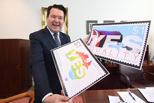 Dean Smith poses for photographs with designs for stamps after the introduction of the Marriage Amendment Bill into the Senate at Parliament House yesterday. (AAP)