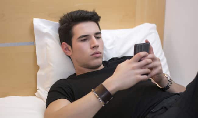 Man holding phone in bed